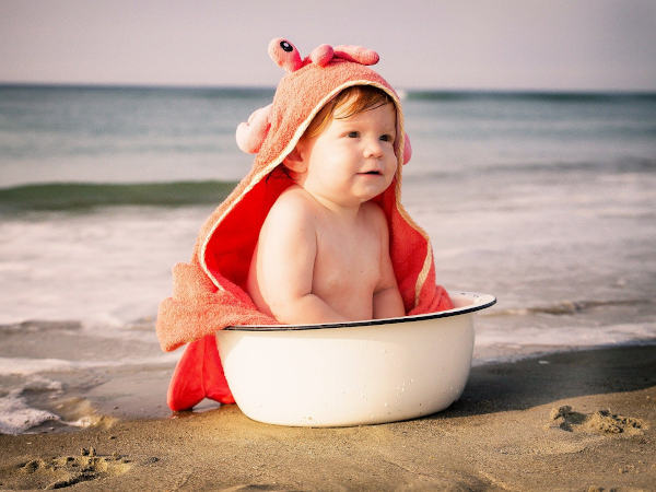 Kleinkind in einer Schüssel sitzend am Strand